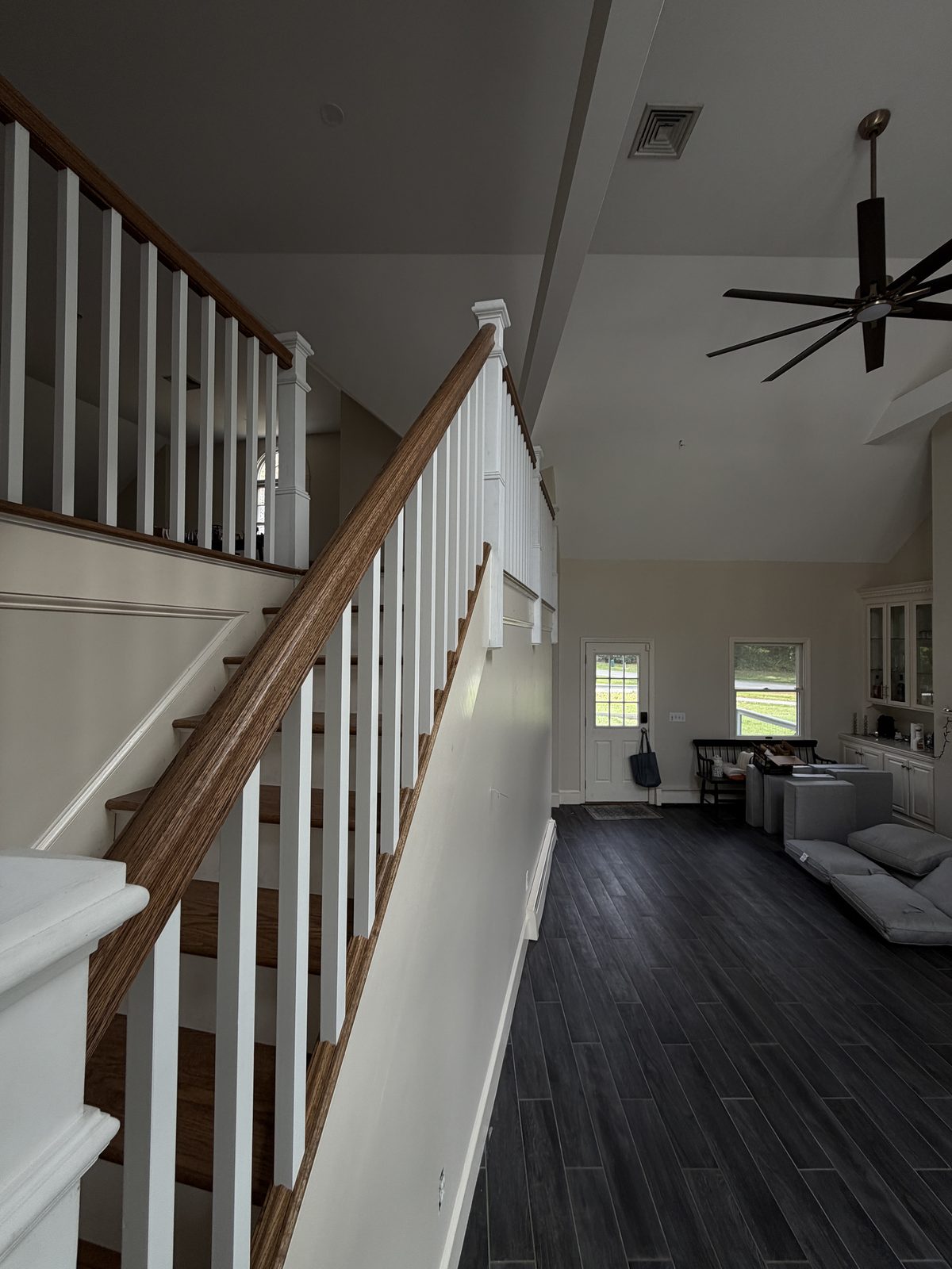 Red oak handrail and square white balusters on the Rehoboth staircase, looking up toward the landing.