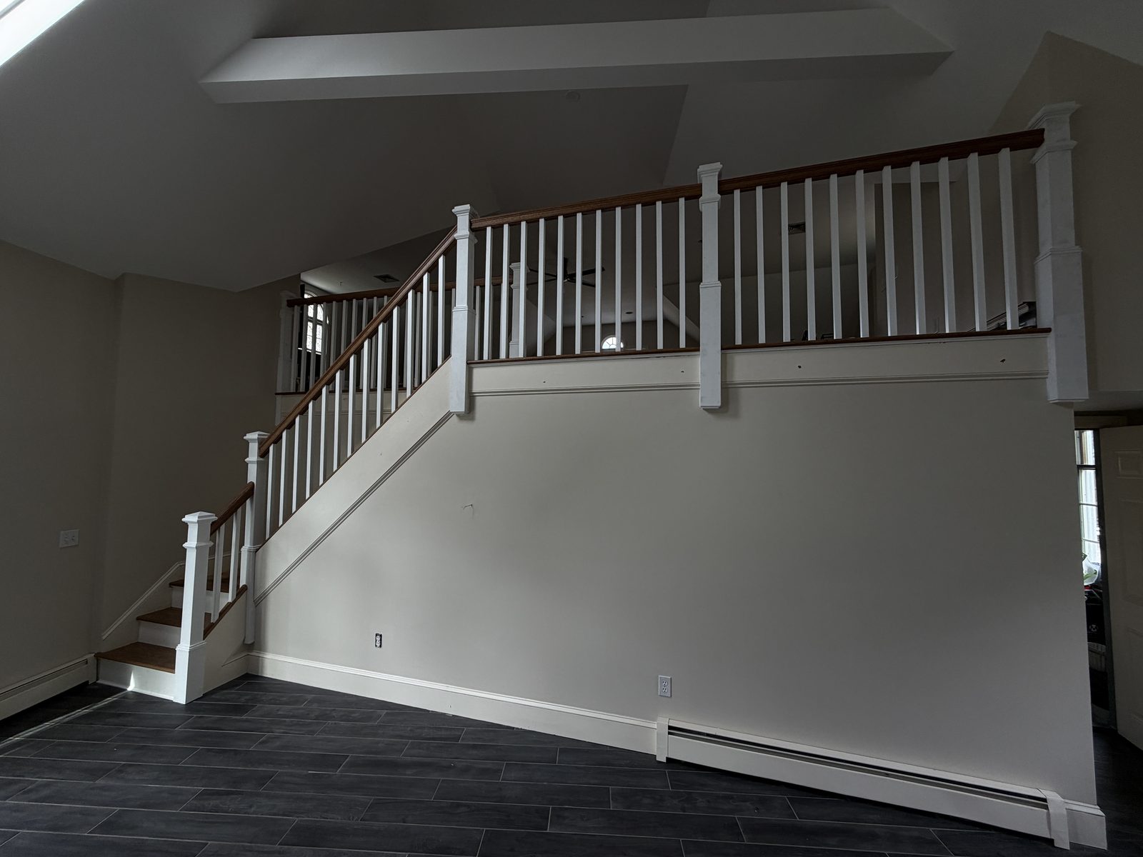 Wide angle of the Rehoboth staircase showing red oak handrails, painted square newel posts and the open railing along the upper landing.