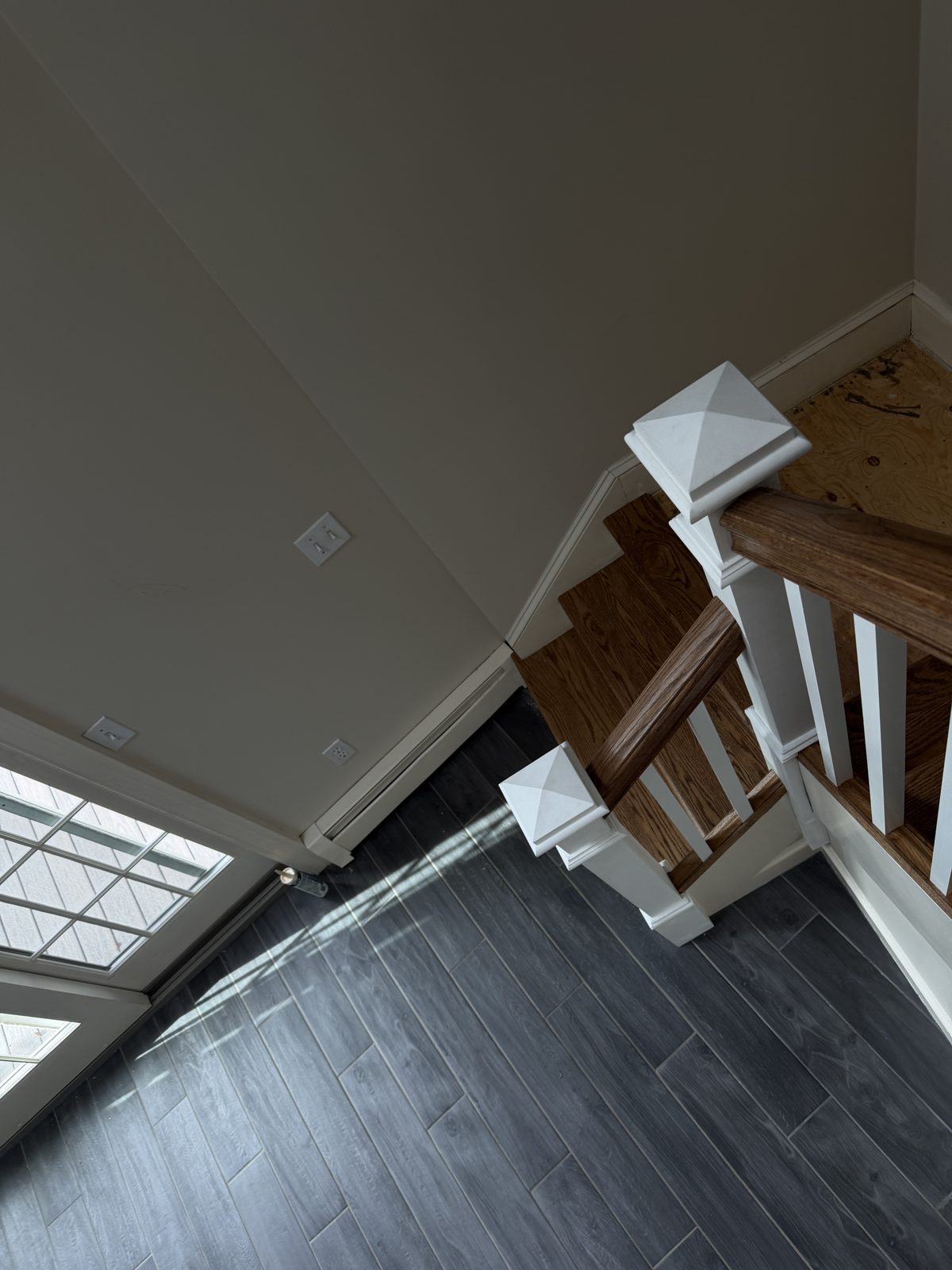 Newel posts with pyramid caps, a red oak handrail and treads coming together at the turn of the staircase during the Rehoboth rebuild.